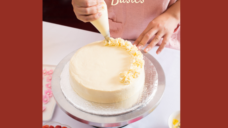 Someone piping frosting onto a cake
